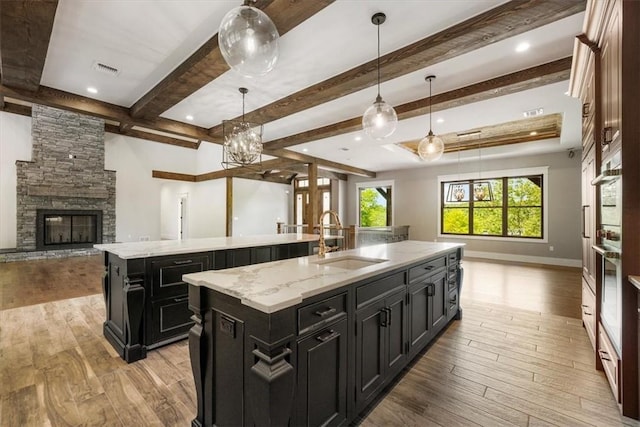 kitchen featuring sink, pendant lighting, light hardwood / wood-style flooring, a fireplace, and a large island