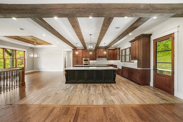 kitchen featuring beamed ceiling, a large island, light hardwood / wood-style floors, and pendant lighting