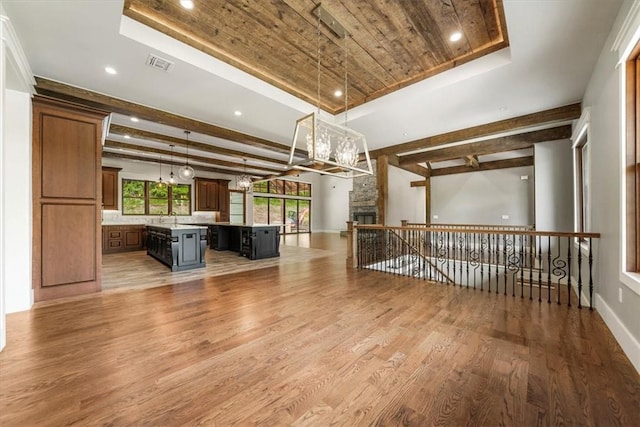 interior space featuring a fireplace, wood-type flooring, a raised ceiling, and wooden ceiling