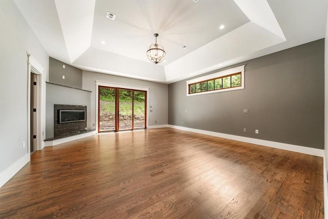 unfurnished living room with hardwood / wood-style flooring, a chandelier, and a tray ceiling