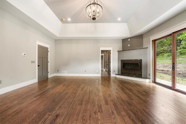 unfurnished living room with a tray ceiling, a premium fireplace, an inviting chandelier, and hardwood / wood-style flooring