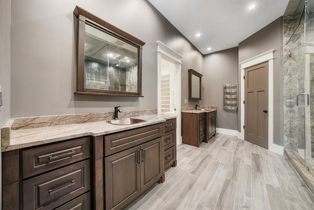 bathroom with hardwood / wood-style floors, vanity, and a shower with shower door