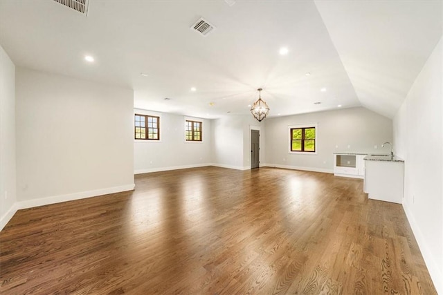 unfurnished living room with hardwood / wood-style floors, an inviting chandelier, lofted ceiling, and sink