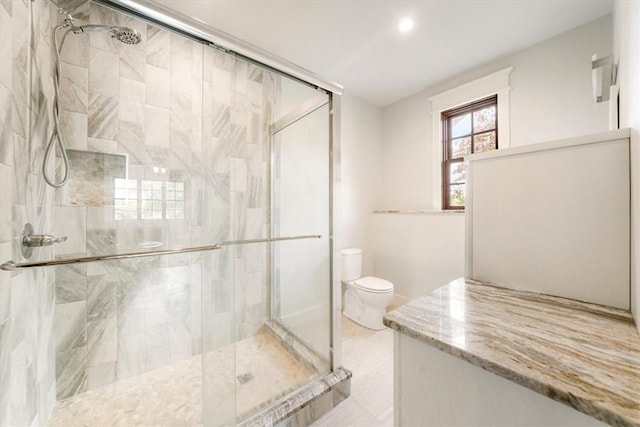 bathroom featuring toilet and a shower with door