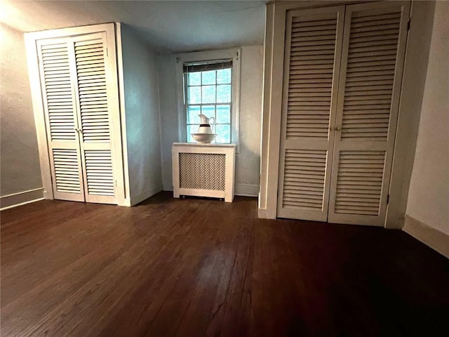 unfurnished bedroom with radiator heating unit and dark hardwood / wood-style floors