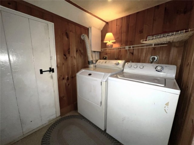 clothes washing area featuring washer and clothes dryer and wooden walls