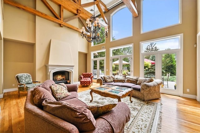 living room featuring a chandelier, french doors, high vaulted ceiling, and light hardwood / wood-style flooring