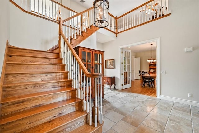 stairway featuring french doors, a high ceiling, and a chandelier