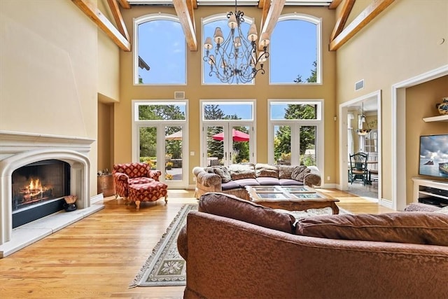 living room with wood-type flooring, a towering ceiling, a wealth of natural light, and french doors