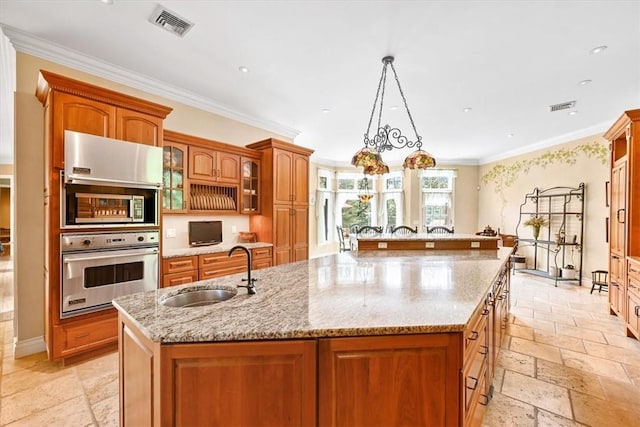 kitchen featuring a center island with sink, decorative light fixtures, crown molding, and sink