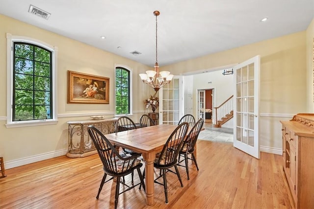 dining space with a chandelier, french doors, and light hardwood / wood-style floors