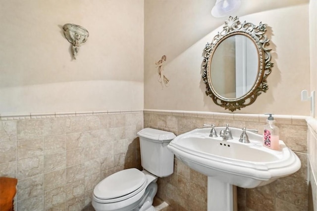 bathroom featuring sink, tile walls, and toilet