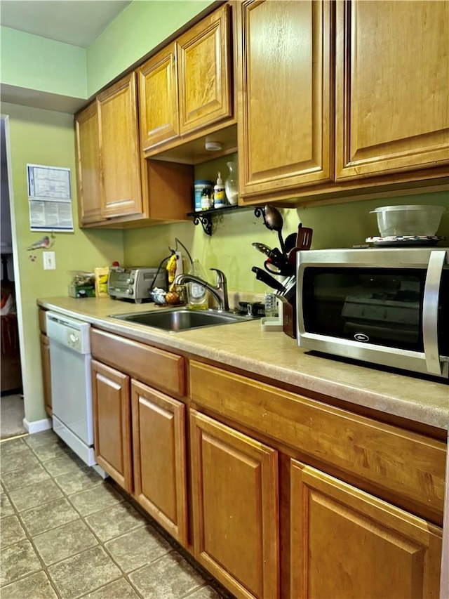 kitchen with dishwasher, light tile patterned floors, and sink