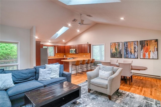 living room featuring a skylight, ceiling fan, light hardwood / wood-style flooring, and a baseboard radiator