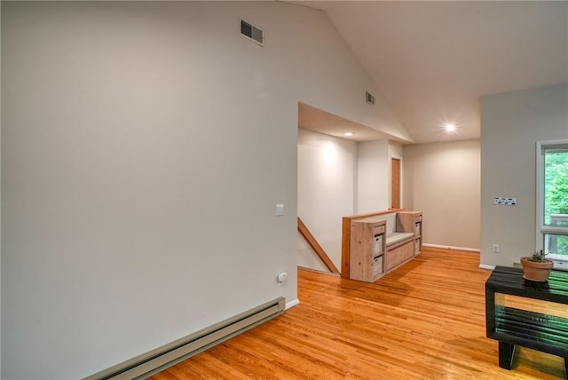 interior space featuring high vaulted ceiling, light wood-type flooring, and a baseboard heating unit