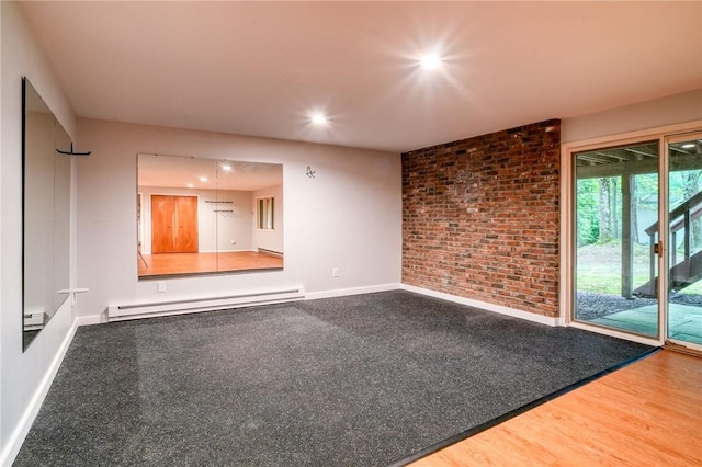 unfurnished room with hardwood / wood-style floors, baseboard heating, and brick wall