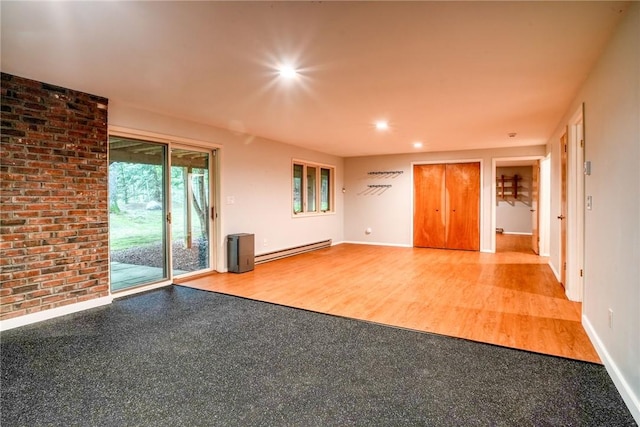 unfurnished room featuring baseboard heating and wood-type flooring