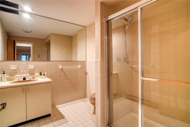 bathroom featuring tile patterned flooring, a shower with door, toilet, and tile walls