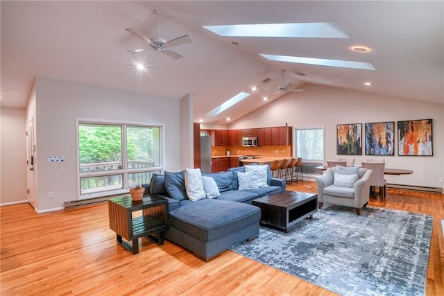 living room featuring ceiling fan, light hardwood / wood-style floors, a baseboard heating unit, and a skylight