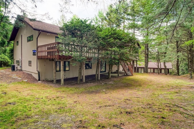 rear view of house featuring a yard, central air condition unit, and a wooden deck