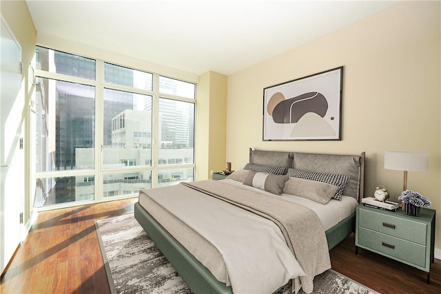 bedroom with dark hardwood / wood-style flooring and a wall of windows