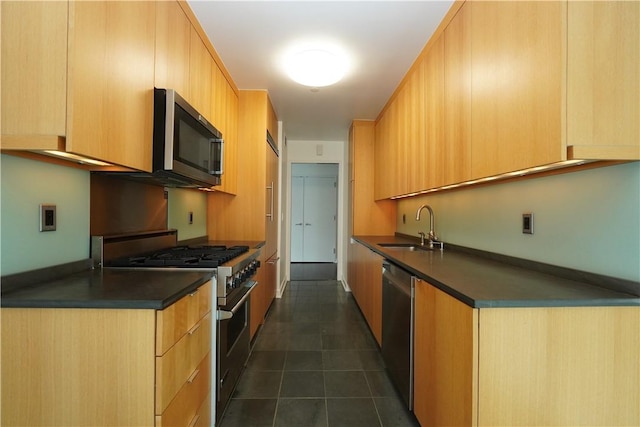 kitchen featuring appliances with stainless steel finishes, dark tile patterned flooring, light brown cabinetry, and sink