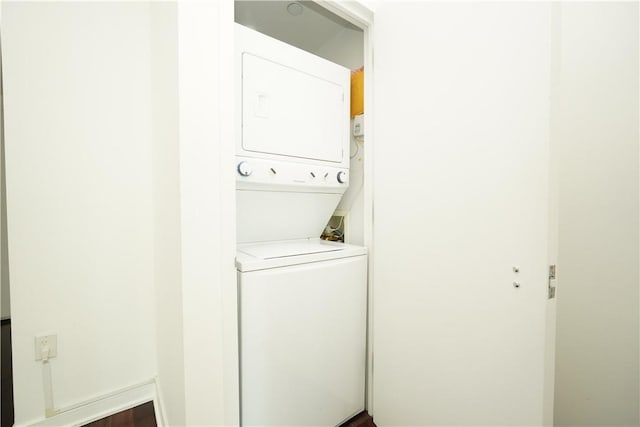 laundry area featuring stacked washer and dryer and dark hardwood / wood-style floors