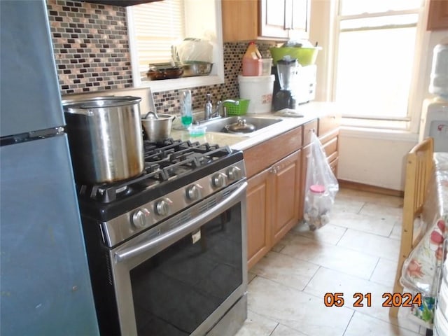 kitchen featuring a sink, appliances with stainless steel finishes, light countertops, light tile patterned floors, and decorative backsplash