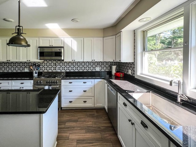 kitchen featuring white cabinetry, sink, backsplash, decorative light fixtures, and appliances with stainless steel finishes