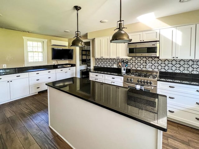 kitchen with appliances with stainless steel finishes, a wall unit AC, dark wood-type flooring, pendant lighting, and white cabinets