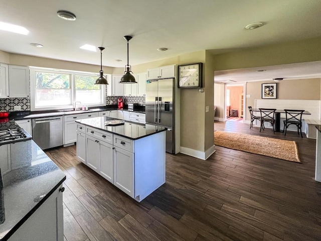 kitchen with pendant lighting, backsplash, dark wood-type flooring, appliances with stainless steel finishes, and white cabinetry