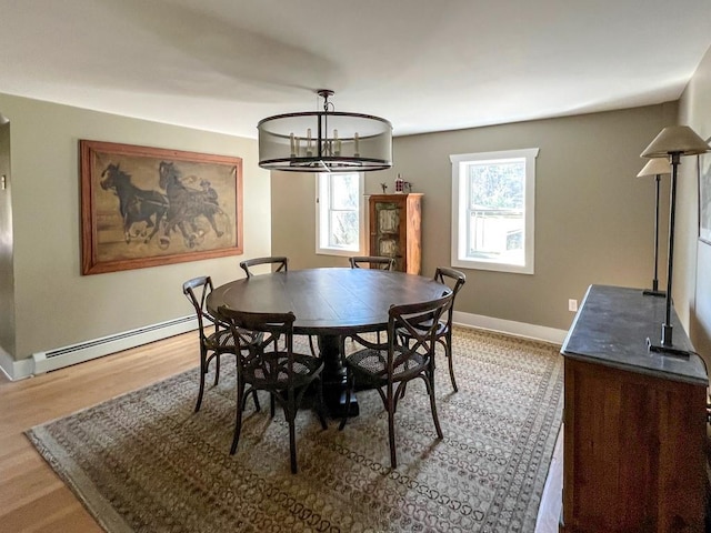 dining space featuring an inviting chandelier, light wood-type flooring, and a baseboard heating unit