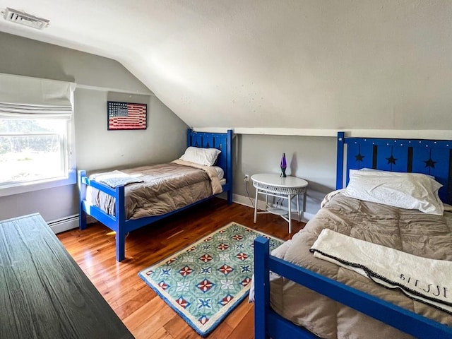 bedroom featuring dark hardwood / wood-style floors, vaulted ceiling, and a baseboard heating unit