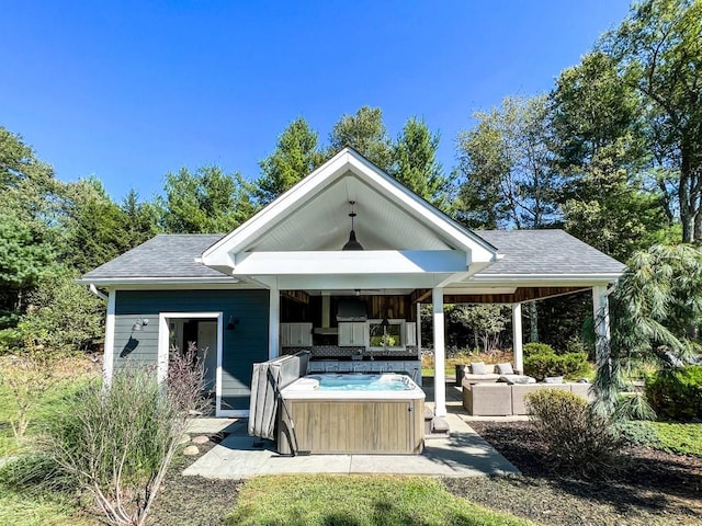 rear view of house with outdoor lounge area, a patio area, and a hot tub