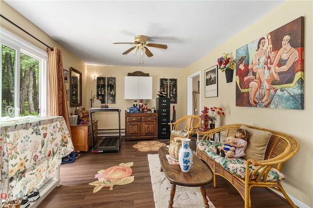 sitting room with ceiling fan, dark wood-type flooring, and a baseboard heating unit