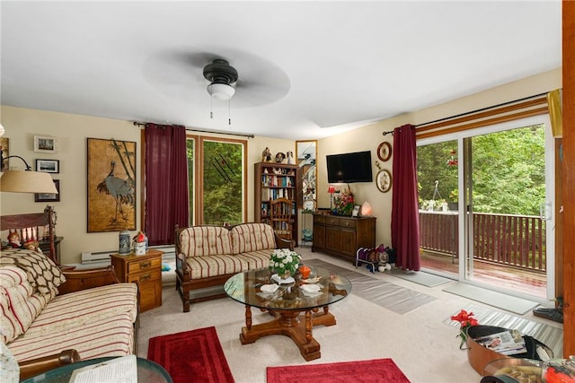 living room with ceiling fan, light colored carpet, a healthy amount of sunlight, and a baseboard heating unit