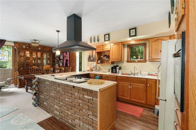 kitchen with sink, dark hardwood / wood-style floors, kitchen peninsula, island exhaust hood, and decorative light fixtures