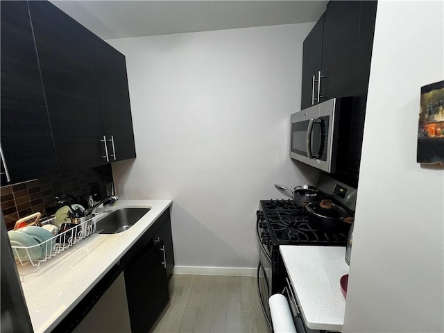 kitchen with tasteful backsplash, light hardwood / wood-style flooring, black appliances, and sink