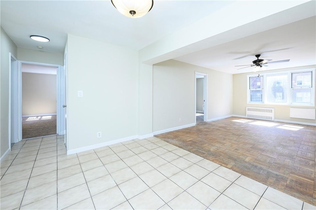 empty room with light parquet floors, radiator, and ceiling fan