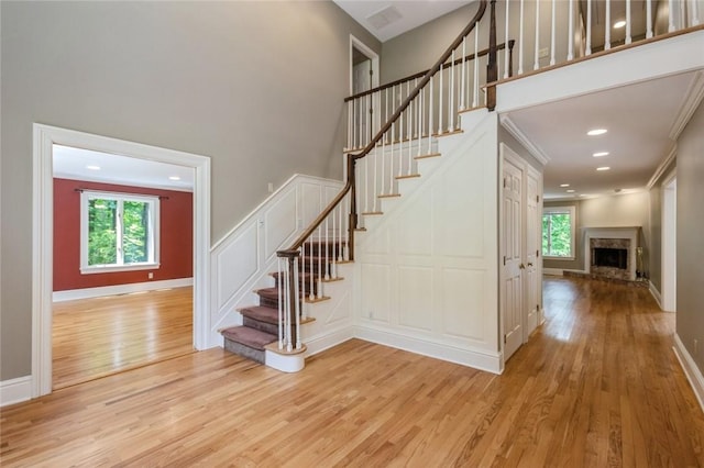 stairway with plenty of natural light, ornamental molding, and hardwood / wood-style flooring