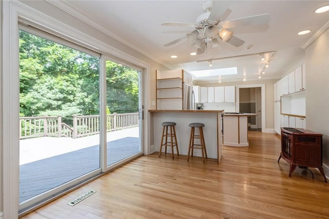 interior space with kitchen peninsula, a kitchen bar, light wood-type flooring, and white cabinetry