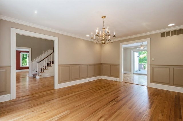 spare room featuring plenty of natural light, light wood-type flooring, ornamental molding, and ceiling fan with notable chandelier