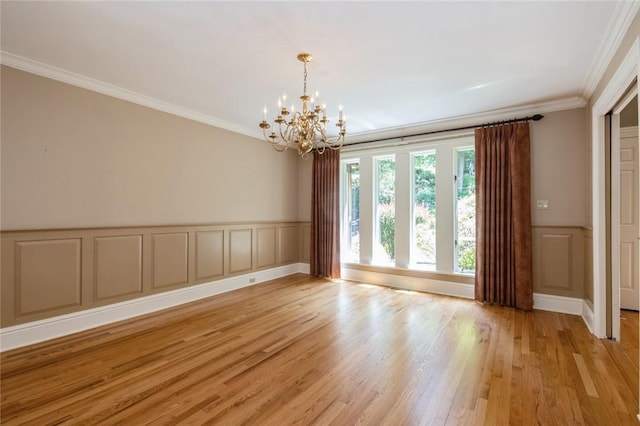 empty room featuring light hardwood / wood-style flooring, crown molding, and an inviting chandelier