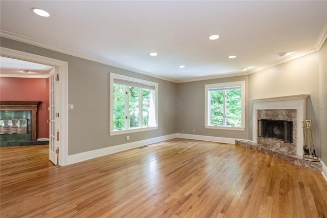 unfurnished living room featuring crown molding, a high end fireplace, and light wood-type flooring