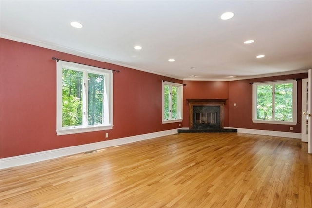 unfurnished living room with light hardwood / wood-style floors, a healthy amount of sunlight, and ornamental molding