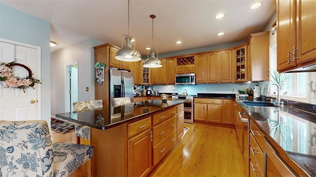 kitchen with a center island, sink, light wood-type flooring, decorative light fixtures, and stainless steel appliances