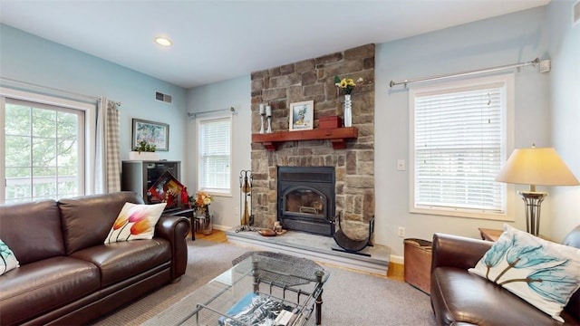 living room with a stone fireplace and carpet floors