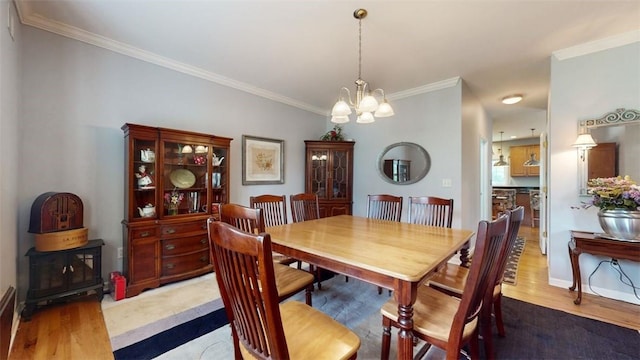 dining space featuring wood-type flooring, an inviting chandelier, and crown molding