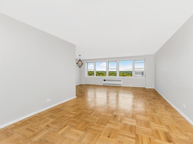 unfurnished living room with a chandelier, radiator heating unit, and light parquet floors