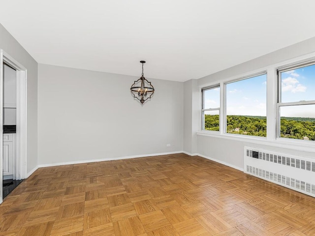 empty room featuring light parquet flooring, an inviting chandelier, and radiator